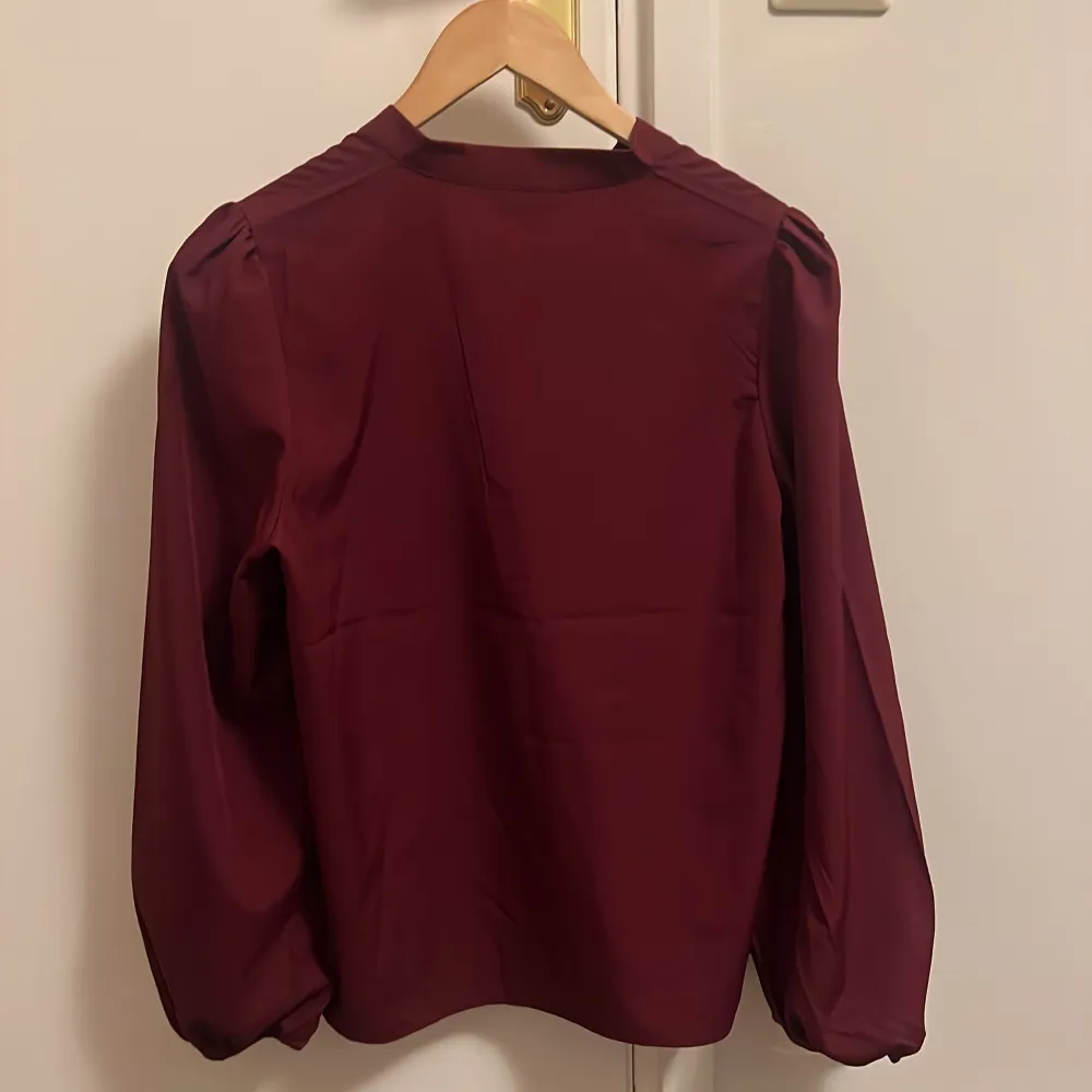 Söt blus med mininal, diskret puffärm. 5 knappar framtill som går att knäppa upp. Resår i armarna nedtill. Oanvänd. . Puserot.