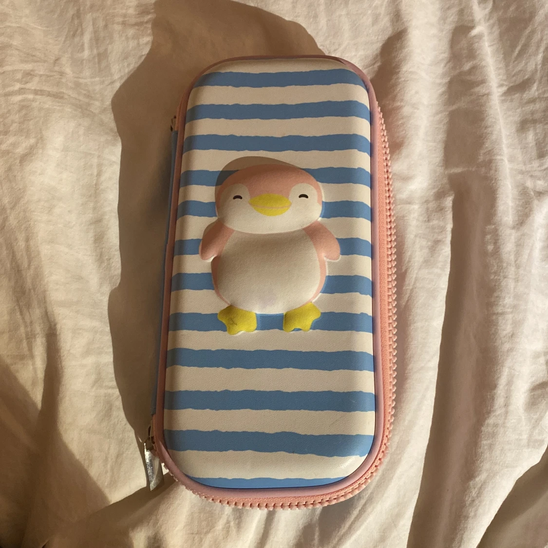 Blå- och vitrandig pennfodral med pingvinmotiv