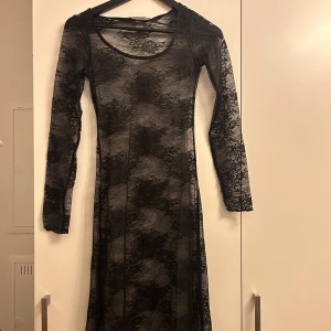 Svart lång spetsklänning - Elegant svart långklänning i spets med långärmad design. Klänningen har en åtsittande passform som framhäver figuren. Jag är 158 och klänningen går ända ner till golvet😊