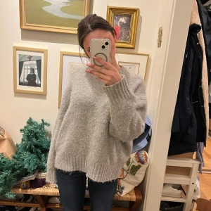 Grå stickad tröja - Mysig grå stickad tröja med lång ärm och ribbade detaljer vid ärmslut och nederkant. Perfekt för kyliga dagar.