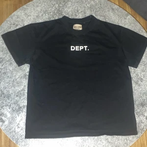 Svart t-shirt från Gallery Dept. - Snygg svart t-shirt från Gallery Dept. med tryck 'DEPT.' på framsidan och detaljerat tryck på baksidan. Perfekt för en stilren och avslappnad look.