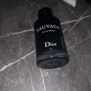 Sauvage Eau de Parfum från Dior - Tja, byter min Dior Sauvage 60ml med cirka 55-58ml kvar kom gärna med förslag. Sauvage Eau de Parfum från Dior är en elegant doft med fräscha och kryddiga noter. Flaskan är mörkblå och stilren med en enkel design. Doften har inslag av citrus, amber, musky och vanilj, vilket ger en sofistikerad och modern känsla.