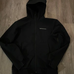Peakperformance vindjacka  - Svart peak performance vindjacka i bra skick förutom ett hål som blivit men lagat med en lapp över men syns knappt vid användning (se andra bilden) där av priset!