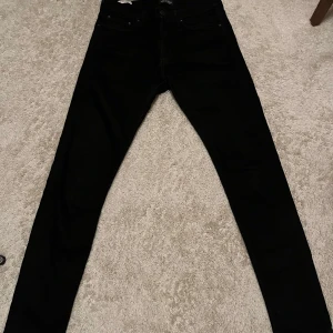 Svarta jeans från Jack & Jones - Snygga svarta jeans från Jack & Jones med en klassisk design. De har en rak passform och är tillverkade i ett slitstarkt material. Storlek W29 och L32. Inga tecken på slitning. 