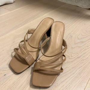 Beige sandaler med klack - Stilrena beige sandaler med klack och smala remmar. 