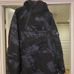 Dope jacka  - Säljer en cool svart och blå camo jacka från Dope. Jackan har en stor ficka framtill med dragkedja och en justerbar huva. Perfekt för höst och vinter med sin stilrena design och funktionella detaljer. Använd en säsong. Nypris 2500