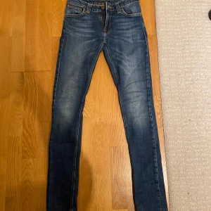 Nudie jeans - Säljer ett par snygga blå jeans från Nudie Jeans. De är tillverkade i 100% ekologisk bomull och har en klassisk femficksdesign. Perfekta för en stilren look. Modellen är skinny och passar perfekt till dagens trender. Storlek W27 och L32