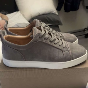 Christian louboutin - Snygga grå sneakers i mocka med vit sula och klassisk snörning. Perfekta för en stilren look. Riktikgt fräsha helt nya och ej kvitto!
