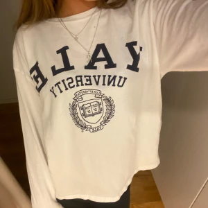 Vit långärmad tröja med Yale-tryck - Säljer en vit långärmad tröja med tryck från Yale University. Tröjan är knappt använd. Den är gjord i ett mjukt material som känns skönt mot huden.