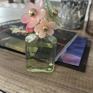Daisy Eau So Fresh från Marc Jacobs - Charmig parfymflaska med blommig design från Marc Jacobs. Flaskan är grön med en unik kork dekorerad med rosa, beige och gröna blommor. Perfekt för den som älskar en fräsch och blommig doft. Ny pris 700 mitt pris 499