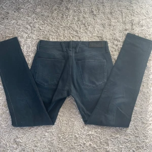 Svarta jeans från Replay - Snygga svarta jeans från Replay med en klassisk design. De har en normal passform och är tillverkade i ett slitstarkt material. Byxorna har dragkedja och knapp framtill samt två bakfickor. Perfekta för en stilren look.