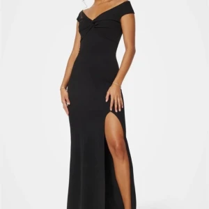 BALKLÄNNING  - Elegant svart långklänning med offshoulder-design och en stilren slits framtill. Klänningen har en vacker knytdetalj vid bysten som ger en extra touch av elegans. Perfekt för en kväll ute eller en speciell tillställning. Pris kan diskuteras!