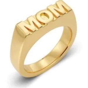 Guldfärgad ring med texten MOM - Stilren guldfärgad ring med texten 'MOM' i blockbokstäver. Perfekt som en personlig present eller för att hylla en speciell mamma. Ringen har en modern och minimalistisk design.