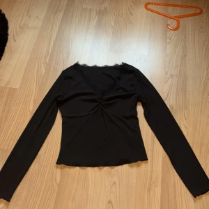 Svart långärmad topp - Snygg svart långärmad topp med v-ringning och rynkdetalj framtill. Perfekt för en stilren look.