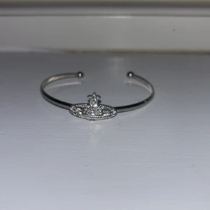 Silverfärgat armband med stjärndetalj - Elegant silverfärgat armband med en unik stjärndetalj i mitten. Armbandet har en öppen design som gör det enkelt att justera efter handleden. Perfekt för att lägga till en gnistrande touch till din stil.