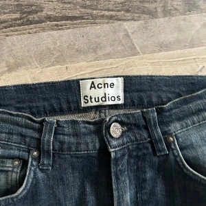 Blå jeans från Acne Studios - Snygga blå jeans från Acne Studios med klassisk design. De har en normal passform och är perfekta för en stilren look. Jeansen har en knappgylf och femficksmodell.