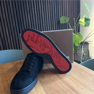 Svarta sneakers från Christian Louboutin - Snygga svarta sneakers i mocka från Christian Louboutin med den ikoniska röda sulan. Skorna har snörning och en stilren design som passar perfekt för en trendig look.
