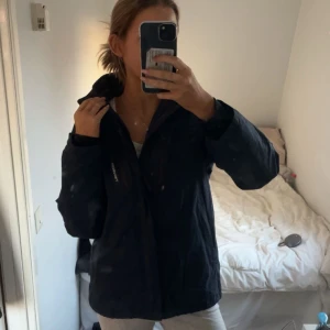 Svart vindjacka från Tenson - Säljer en mörkblå vinter/ höst jacka från Tenson med dragkedja. Jackan har två bröstfickor med dragkedjor men även dragkedjor på sidorna. Jackan håller värme väldigt bra och är i storlek 164 men passar mig som har S i vanliga fall som ni kan se på bilden. Ordinare pris: 1400 kr. 