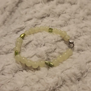Pärlarmband med gröna detaljer - Snyggt armband med ljusa pärlor och gröna detaljer. Armbandet har en enkel låsning och passar perfekt för att ge en subtil färgklick till din outfit.