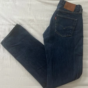 Levis 501 jeans - Klassiska Levis 501 jeans i en snygg blå färg. De har en rak passform och är tillverkade i slitstarkt denim. Perfekta för en avslappnad stil med den ikoniska Levis-lappen på baksidan. De är i mycket bra skick och är i storlek W30 och L32