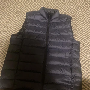 Svart dunväst - Snygg svart dunväst med dragkedja framtill. Perfekt för kyligare dagar och enkel att matcha med olika outfits.