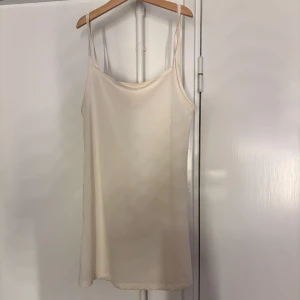Beige linnetopp - Säljer en stilren beige klänning med smala axelband. Perfekt för varma dagar eller som lager under andra plagg. Enkel och tidlös design som passar till det mesta.
