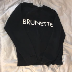 Svart sweatshirt från Brunette the Label - Säljer en svart sweatshirt från Brunette the Label med texten 'BRUNETTE' i vitt på framsidan. Tröjan har långa ärmar och en klassisk rund halsringning. Perfekt för en avslappnad stil.