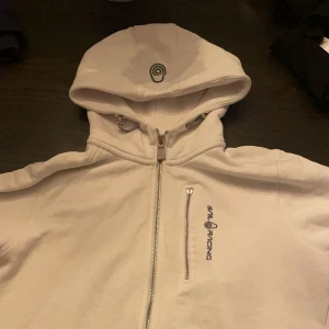Vit hoodie från Sail Racing - Säljer min Sail racing hoodie i storlek 170 bra skick förutom att zipen på brösten har gått av pga detta så säljer jag väldigt billigt. Om du har frågor så kan du skriva och pris är alltid förhandlingsbart 💯