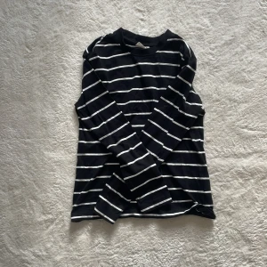 Svart och vit randig långärmad tröja - Säljer en stilren svart och vit randig långärmad tröja. Perfekt för en avslappnad look. Tröjan har en klassisk rund hals och är tillverkad i ett mjukt material.