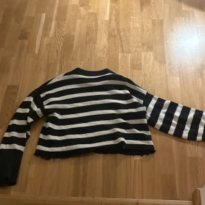 Randig stickad tröja från Gina Tricot - Säljer en snygg randig stickad tröja från Gina Tricot i svart och vit. Tröjan har en croppad design och långa ärmar, perfekt för en trendig look. Passar bra till både jeans och kjol. 🖤🤍