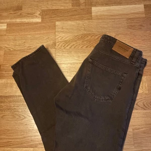 Bruna jeans , Jack & Jones - Snygga bruna jeans från Jack & Jones med en klassisk femficksdesign. De har en normal passform och är perfekta för en avslappnad stil. Jeansen har en knappgylf och är tillverkade i ett slitstarkt material.