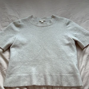 Vit kortärmad tröja - Säljer en vit cashmir tröja med korta ärmar och rund hals. Tröjan har ribbade detaljer vid ärmslut och nederkant, vilket ger en snygg touch. Perfekt för en minimalistisk look.