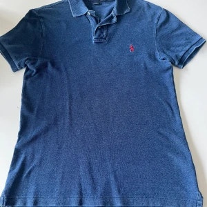 Marinblå pikétröja från Ralph Lauren - Säljer en stilren blå pikétröja från Ralph Lauren i slim fit. Använd flitigt och därför inga defekter. Strl M 