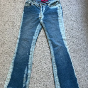 Blå bootcut jeans med blekta detaljer - Snygga blå bootcut jeans med unika blekta detaljer längs benen. Midjemått: 75cm Innerbenslängd: 77cm ❤️