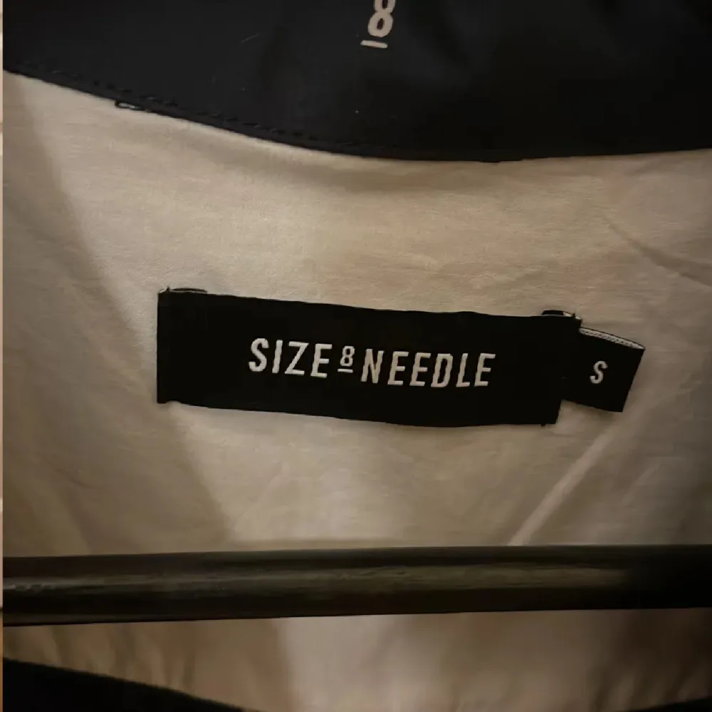 Snygg mörkblå skjorta från Size by Needle med diskret mönster. Skjortan har långa ärmar och en klassisk krage. Perfekt för en stilren look.. Paidat.