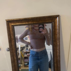 Randig croppad tröja - Randi croppad tröja i rött och beige. Tröjan har långa ärmar och en tight passform, perfekt för en trendig look. Passar bra till jeans eller kjol. 