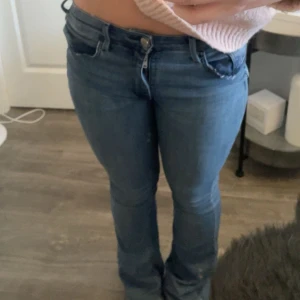 Blå lågmidjade jeans - Snygga blå jeansbyxor med en klassisk design. De har en normal passform och är perfekta för en avslappnad stil. Byxorna har en knapp och dragkedja framtill samt fickor både fram och bak.