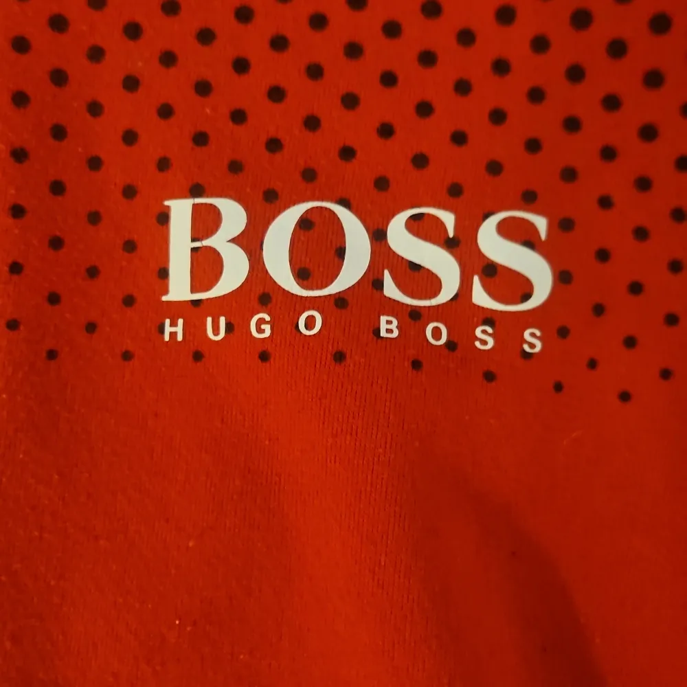 Säljer en snygg röd fleecejacka från Hugo Boss med svarta prickar upptill. Jackan har en dragkedja framtill och en huva för extra komfort. Perfekt för kyliga dagar!. Takit.