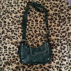 Svart axelväska med kedjedetaljer - Cool svart axelväska med kedjedetaljer och nitar. 