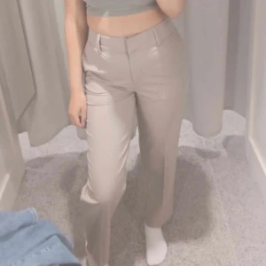 Beige kostymbyxor - Snygga beige kostymbyxor med hög midja och rak passform. Perfekta för en stilren look. Byxorna har knappar och dragkedja framtill.