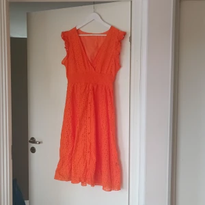 Orange klänning från Shein - Säljer en superfin orange klänning från Shein i storlek XL.  (skulle dock säga att den är mer L) Den har en v-ringad design och är ärmlös med volangdetaljer vid axlarna. Klänningen är i ett lätt och luftigt material, perfekt för sommaren. Den har också ett elastiskt band i midjan för en bekväm passform och små knappar framtill som en söt detalj.