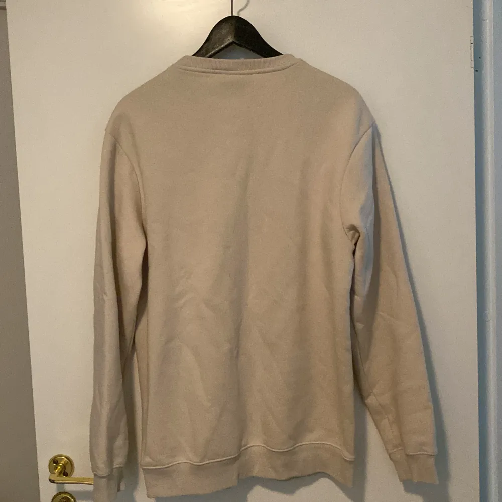 Säljer en stilren beige sweatshirt från H&M i storlek M. Den har en avslappnad passform och är perfekt för både vardag och mysiga stunder. Tröjan är långärmad och har en klassisk rund halsringning. Perfekt för höst och vår!. Tröjor & Koftor.