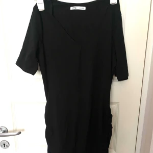 Svart klänning från Zara - Säljer en stilren svart klänning från Sinsay i storlek XL. Klänningen har en enkel design med korta ärmar och en v-ringad hals. Perfekt för både vardag och fest!