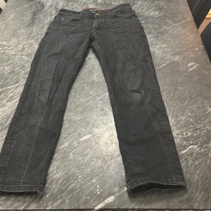 Svarta jeans från Tommy Hilfiger - Säljer ett par snygga svarta jeans från Tommy Hilfiger. De har en klassisk design med knapp och dragkedja framtill. Jeansen är i storlek 152 och har en stilren look med märkets logga på fickan. Perfekta för både vardag och fest! Köpte för 1300kr 