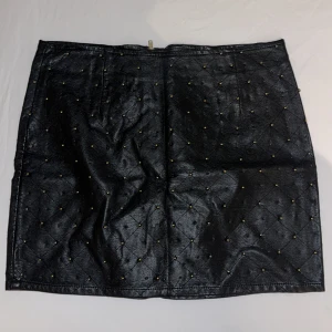 Svart kjol med nitar - Säljer en supercool svart kjol i skinnimitation med små nitar över hela. Den har en dragkedja bak som ger en edgy look. Perfekt för en utekväll eller fest! 🖤Den har inte tappat nitar, som det kan se ut på bilden, utan det är nitarna på andra sidan från att den varit vikt.