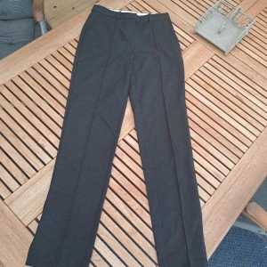 Eleganta Kostymbyxor - Sparsamt använda kostymbyxor. Ser ut som nya och har en liten slits vid byxbenen. Byxorna har både knapp, dragkedja och nån typ av metallspänne. Snygga fejk fickor på baksidan, men dom har framfickor. Säljer för att dom tyvärr är för små. 🤍🤍