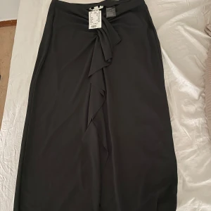 Långkjol - Långkjol med volang, slits. Aldrig använd 