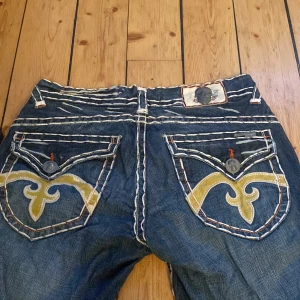 Lowwaist bootcut jeans med coola detaljer - Jättesnygga lowwaist bootcut jeans från laguna beach med jättecoola detaljer Innerbenslängden är 86cm, midjemåttet är 41 rakt över och det är 22 cm från skrevet upp!!
