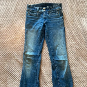Lågmidjade Jeans - Blå bootcut jeans med knappar på fickorna. Bra skick. Säljer eftersom det inte är min stil längre. De är för kort på mig som är 162. Pris kan såklart diskuteras!🥰