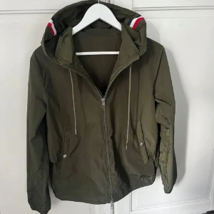 Mocler Windbreaker (olivgrön) - Säljer en Moncler windbreaker jacka i färgen olivgrön som är storlek M/L jackan är i nyskick och säljs för billigt pris:) jackan är såklart äkta och sälj pågrund av att den inte används.
